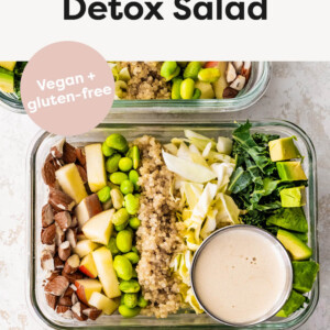 Three glass storage containers layered with detox salad ingredients: almonds, apple, edamame, quinoa, cabbage, kale and avocado. A small container of dressing is also in each of the containers.