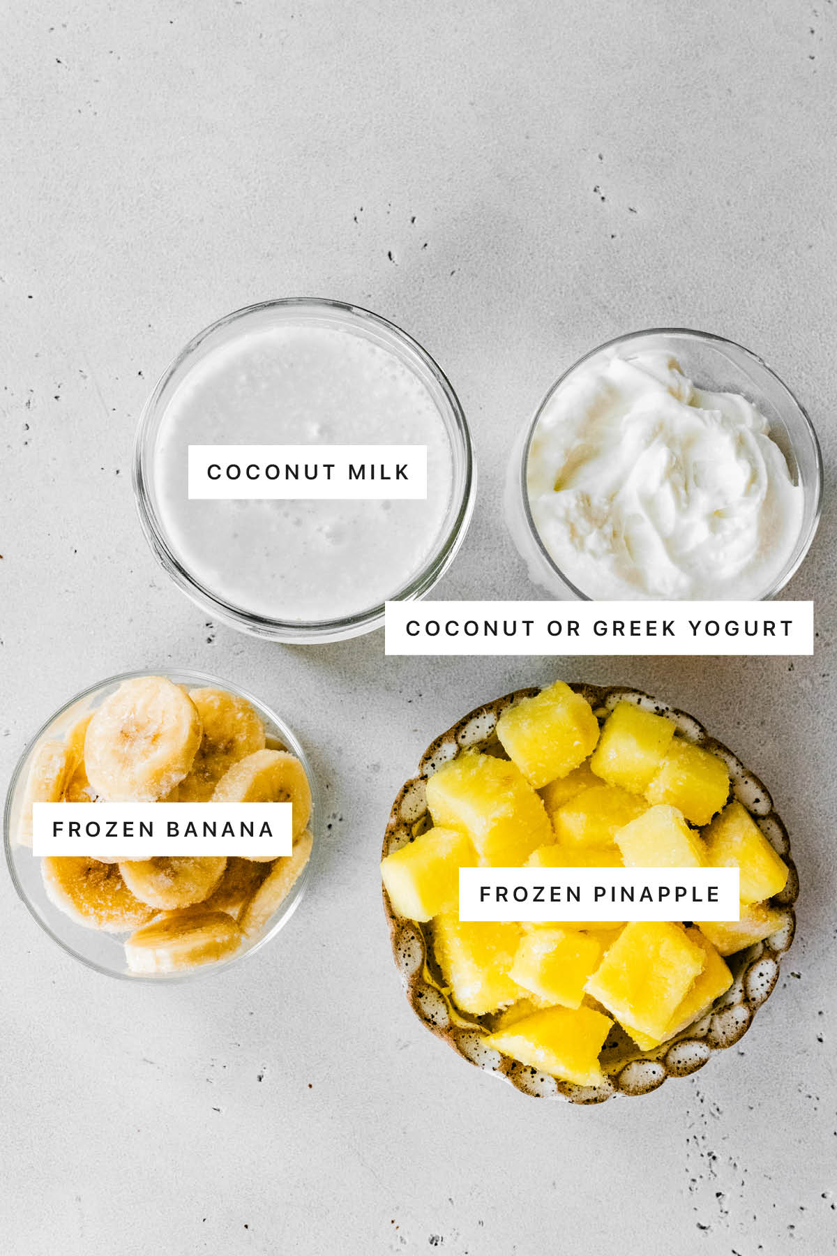 Ingredients measured out to make Pineapple Smoothie: coconut milk, coconut or Greek yogurt, frozen banana and frozen pineapple.