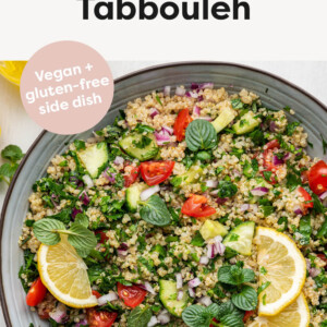 Serving bowl with quinoa tabbouleh garnished with lemon and herbs.