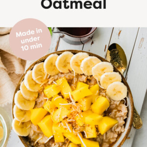 Bowl of oatmeal topped with fresh mango, banana slices, toasted coconut and a splash of milk.