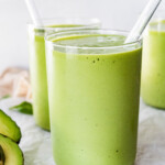 Two avocado smoothies with straws.