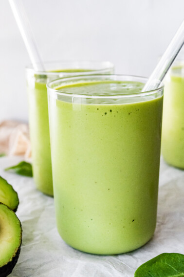 Two avocado smoothies with straws.