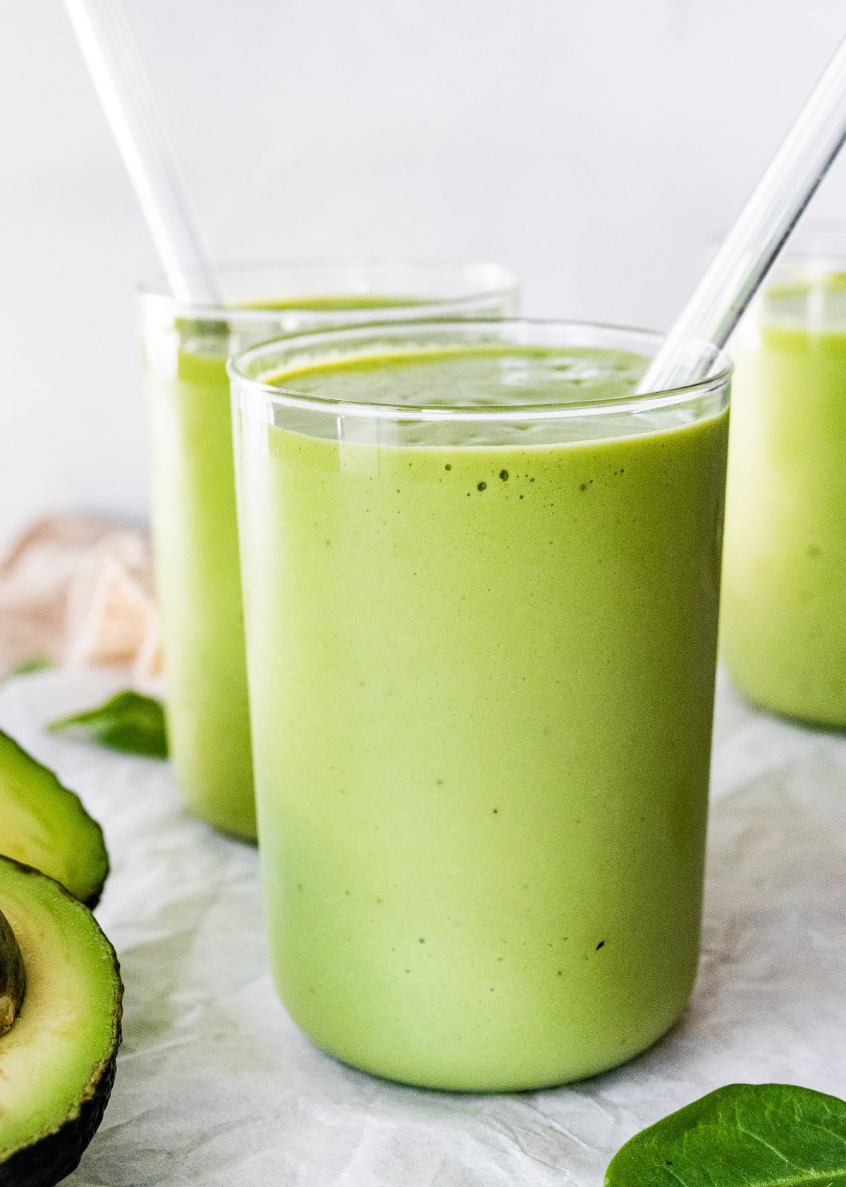 Two avocado smoothies with straws.