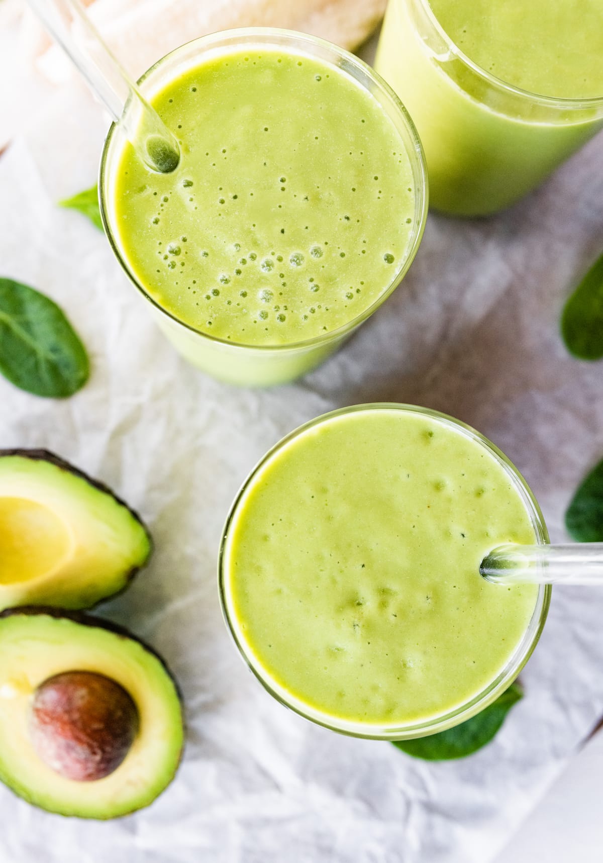 Two avocado smoothies with straws.