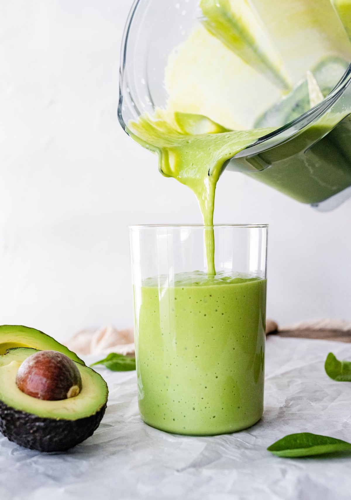 Avocado smoothie being poured into glass.