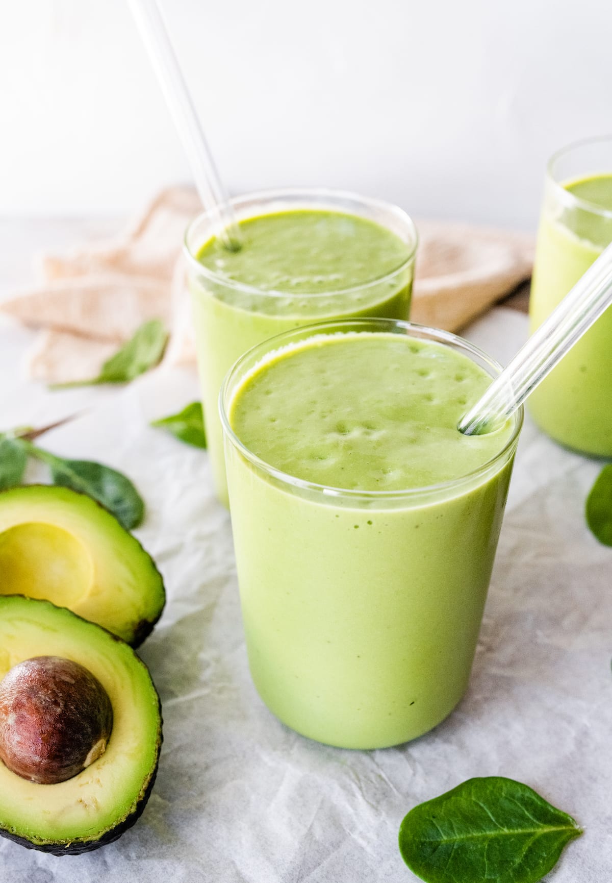 Two avocado smoothies with straws.