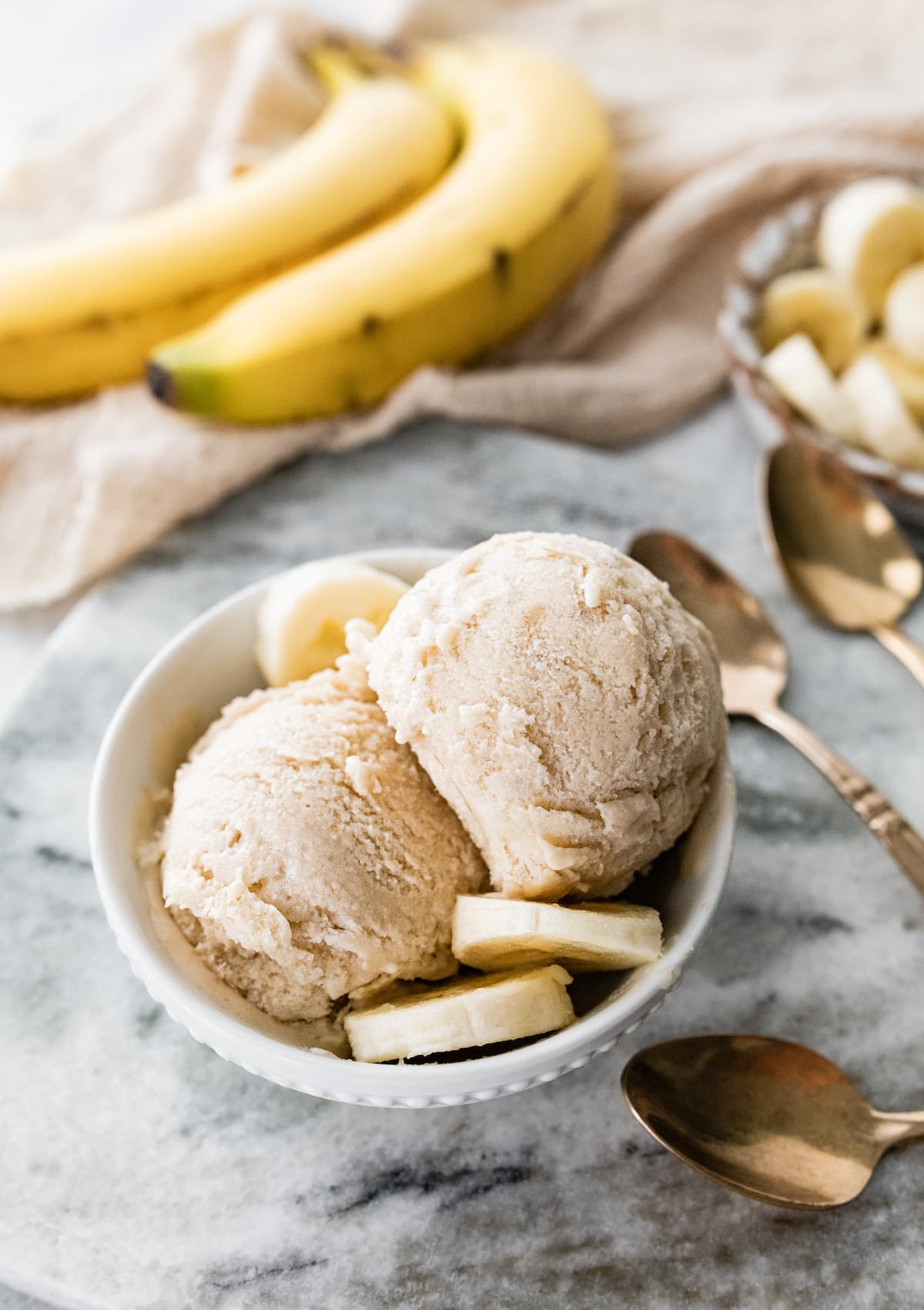 Bowl with two scoops of banana frozen yogurt served with fresh banana slices.
