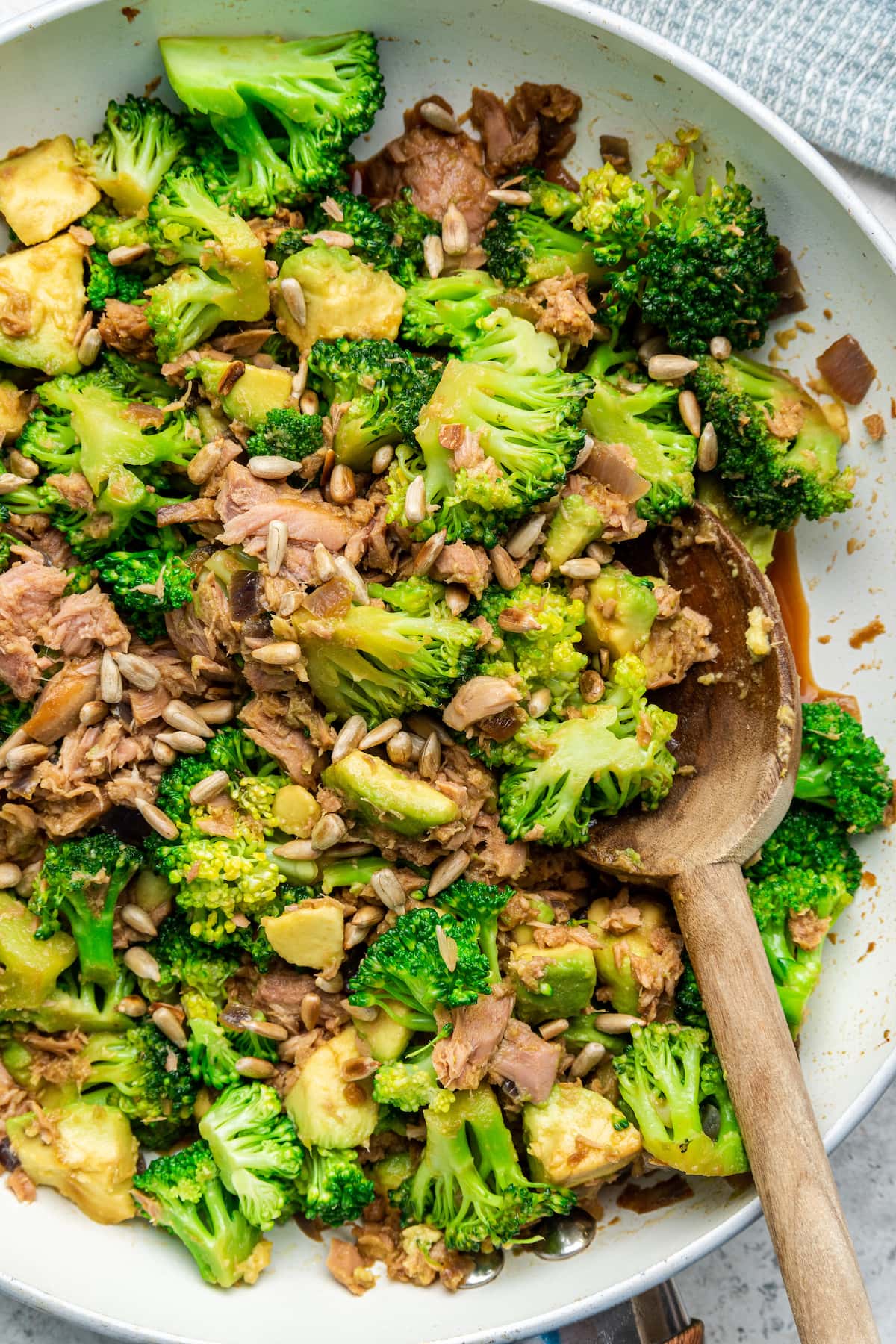 Broccoli avocado tuna bowl in a skillet with wooden serving spoon.