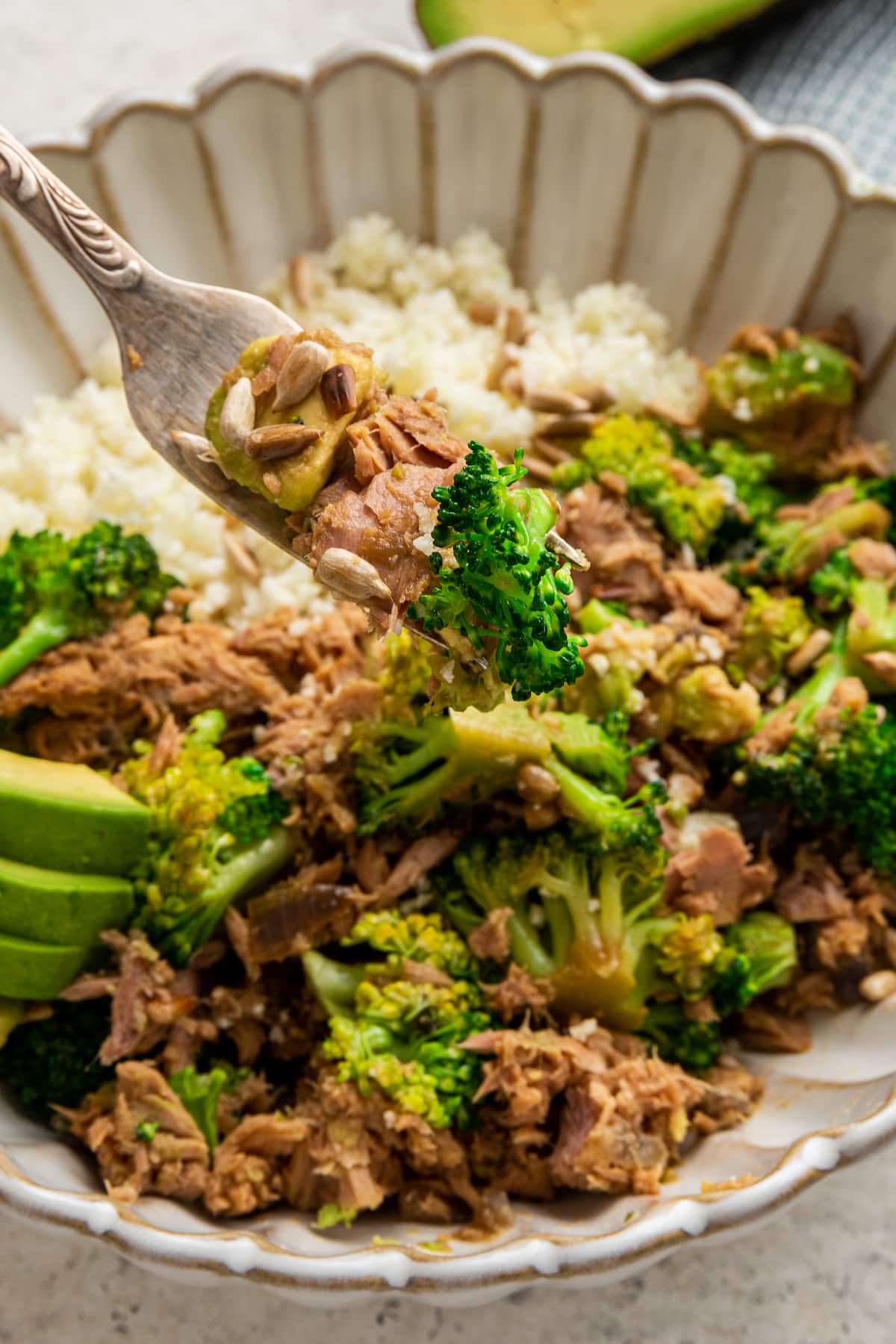 A bite of broccoli avocado tuna bowl with fork.