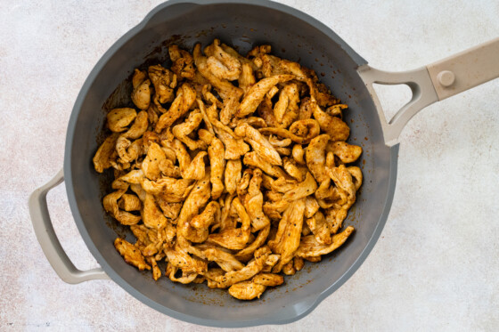 Cooked chicken in a pan for chicken fajita bowls.