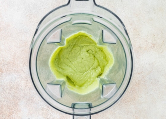 Avocado sauce for chicken fajita bowls blended up in the bowl of a blender.