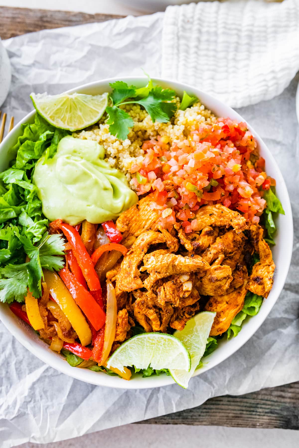 One chicken fajita bowl, topped with pico de gallo, avocado sauce, fresh cilantro and lime wedges.