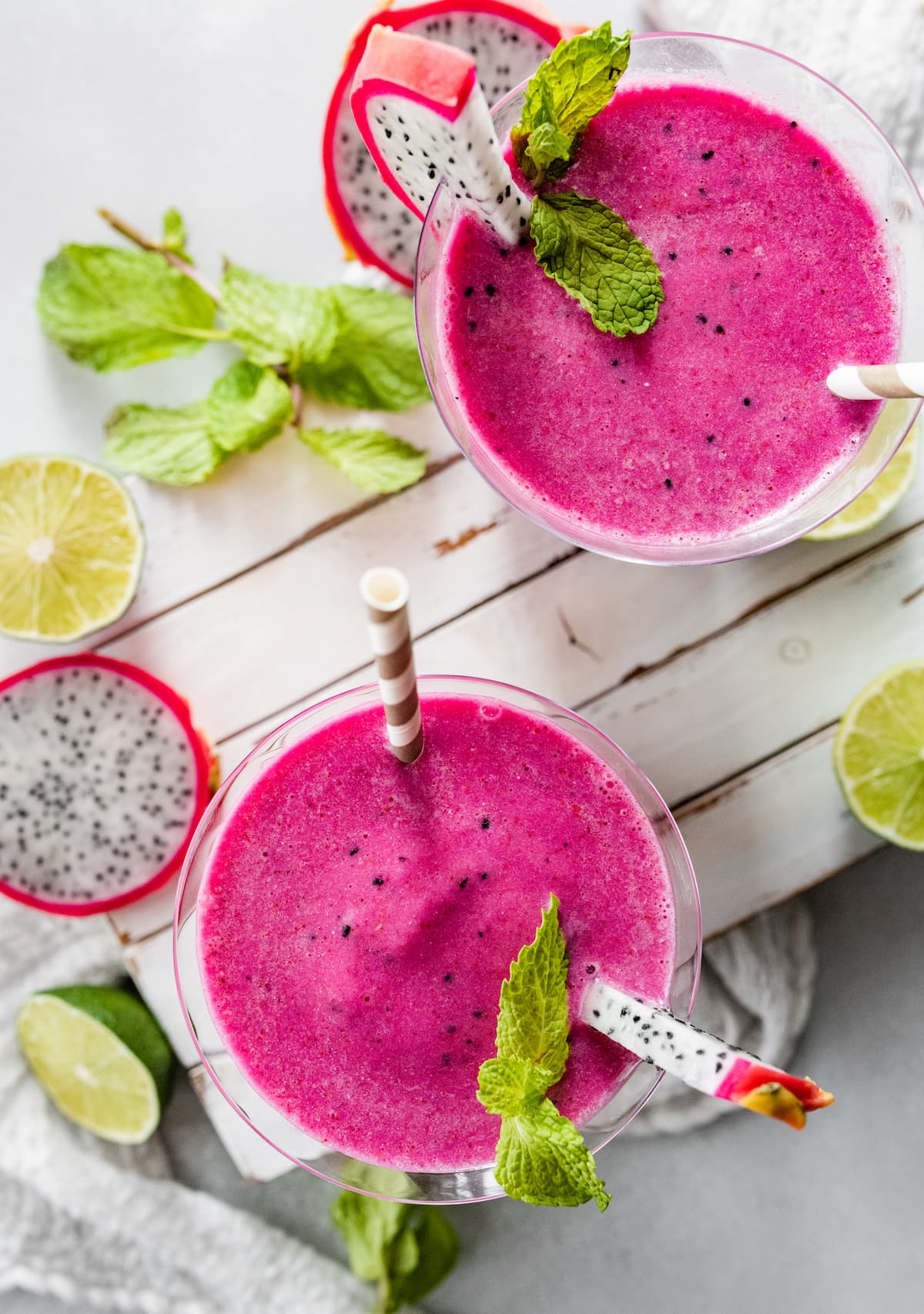 The top of two dragon fruit smoothies in glasses topped with fresh mint and fresh dragon fruit.