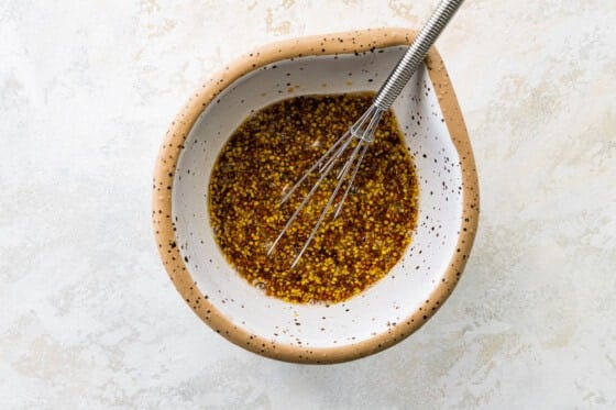Mustard maple dressing for salmon combined in a small mixing bowl with a small whisk.
