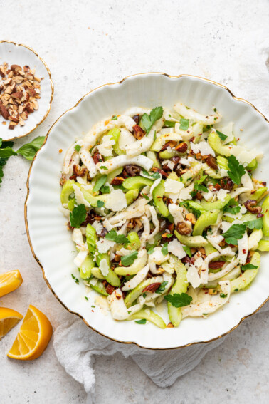 Close up image of fennel and celery salad in white serving bowl.