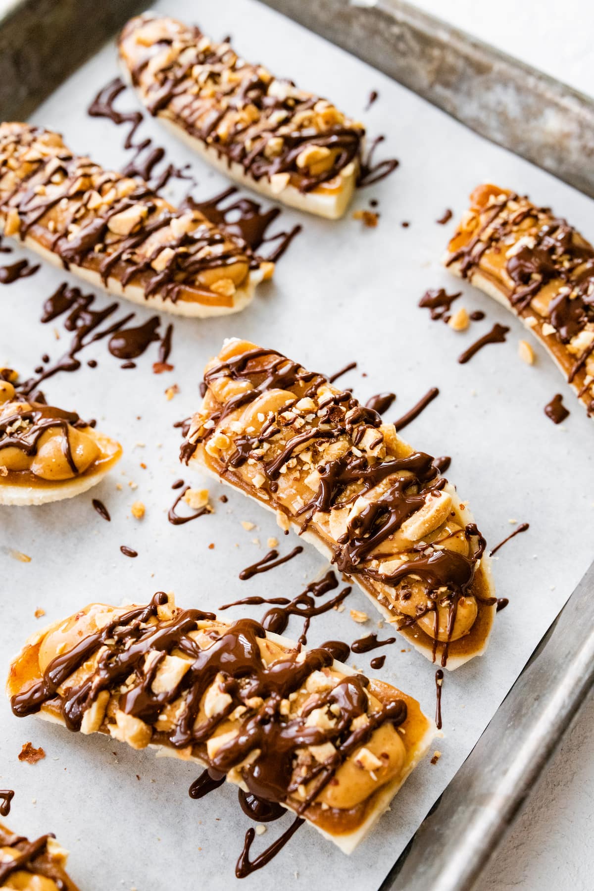 Frozen banana snickers on a baking tray with parchment paper.