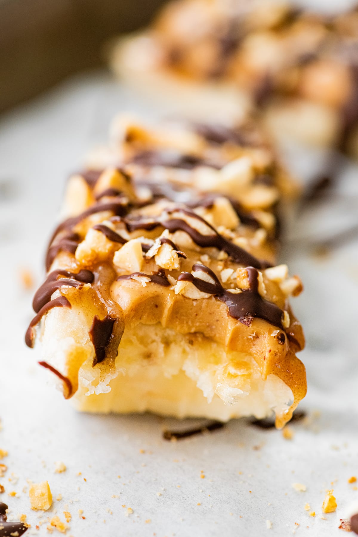 Close up of a frozen banana snickers with a bite taken out of it.