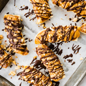 Frozen banana snickers on a baking tray with parchment paper.