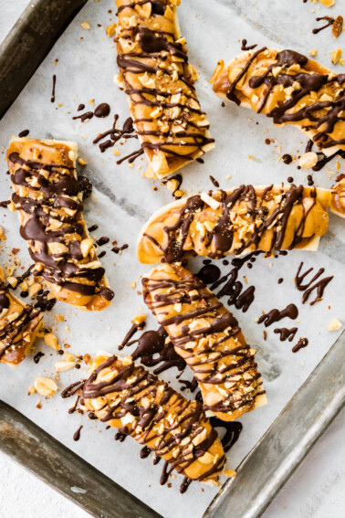 Frozen banana snickers on a baking tray with parchment paper.