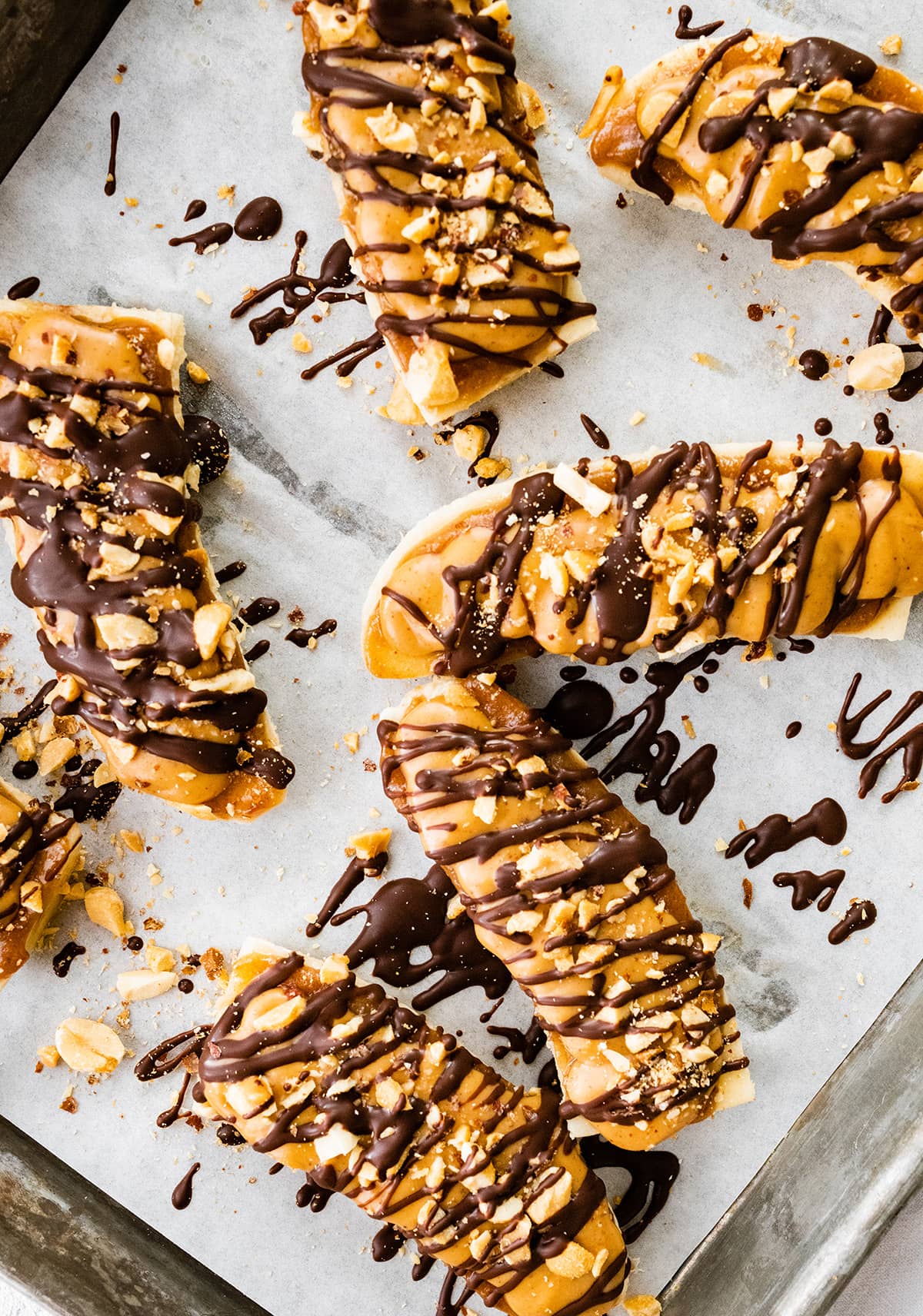 Frozen banana snickers on a baking tray with parchment paper.