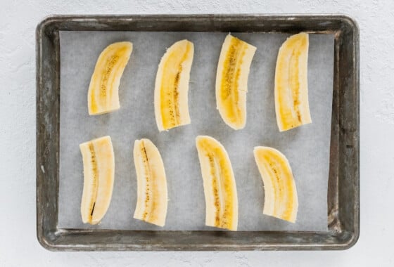8 banana halves on a baking tray lined with parchment paper.