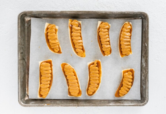 8 banana halves on a baking tray lined with parchment paper each with a layer of date caramel and peanut butter.