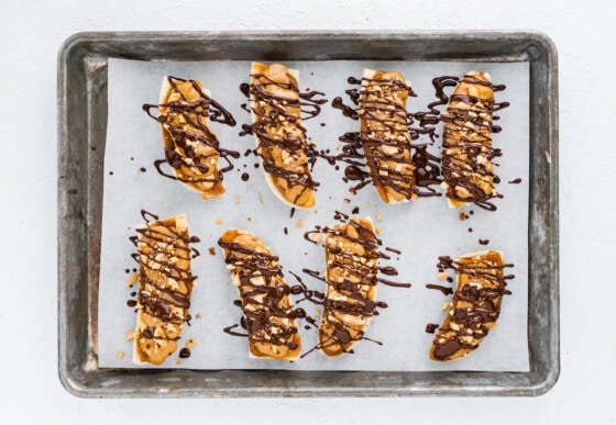 8 frozen banana snickers on a baking tray lined with parchment paper.