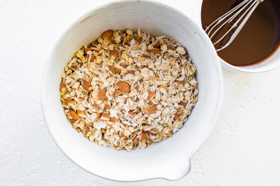 Dry rolled oats, almonds and shredded coconut in a mixing bowl.