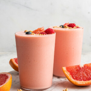 Two grapefruit smoothies served on a marble tray.