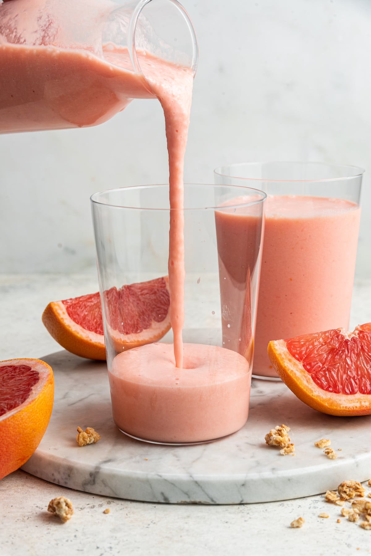 This grapefruit detox smoothie is loaded with nutrients to help diminish bloating, boost your metabolism and get you feeling your best! The perfect way to reset after indulging in too many cocktails, traveling and/or celebrating. Grapefruit smoothie being poured into glass.