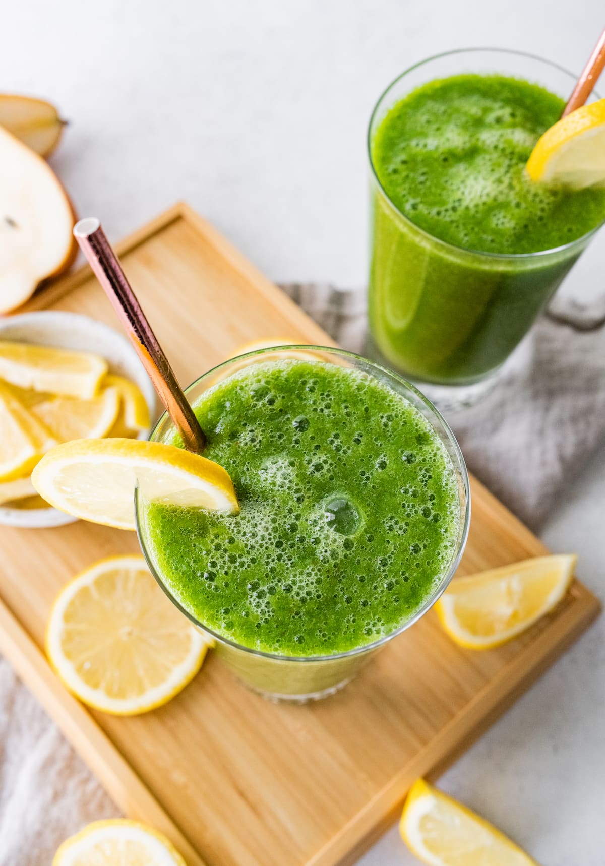 Overhead view of two green lemonade smoothies in glasses.