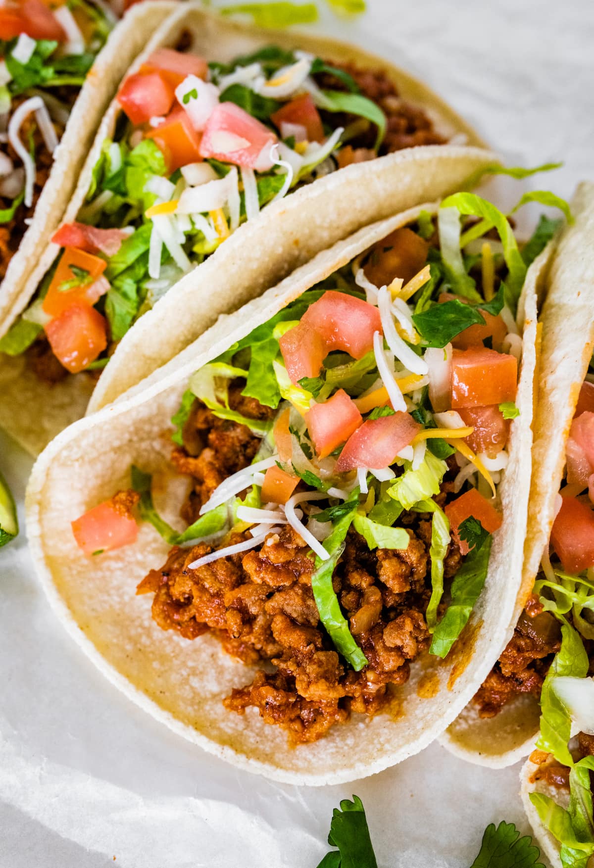 A few ground turkey tacos served in tortillas and topped with lettuce, tomatoes, shredded cheese and cilantro.