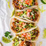 Five ground turkey tacos served in tortillas and topped with lettuce, shredded cheese, tomatoes and cilantro.