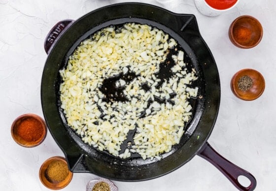 Onions and garlic cooking in a cast iron skillet.