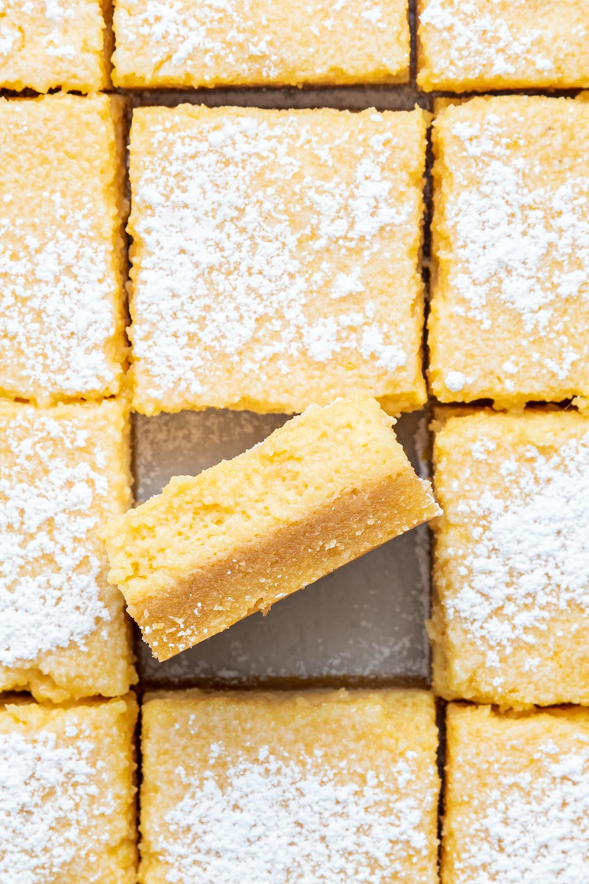 Close up photo of lemon bars in a row with one bar on its side.
