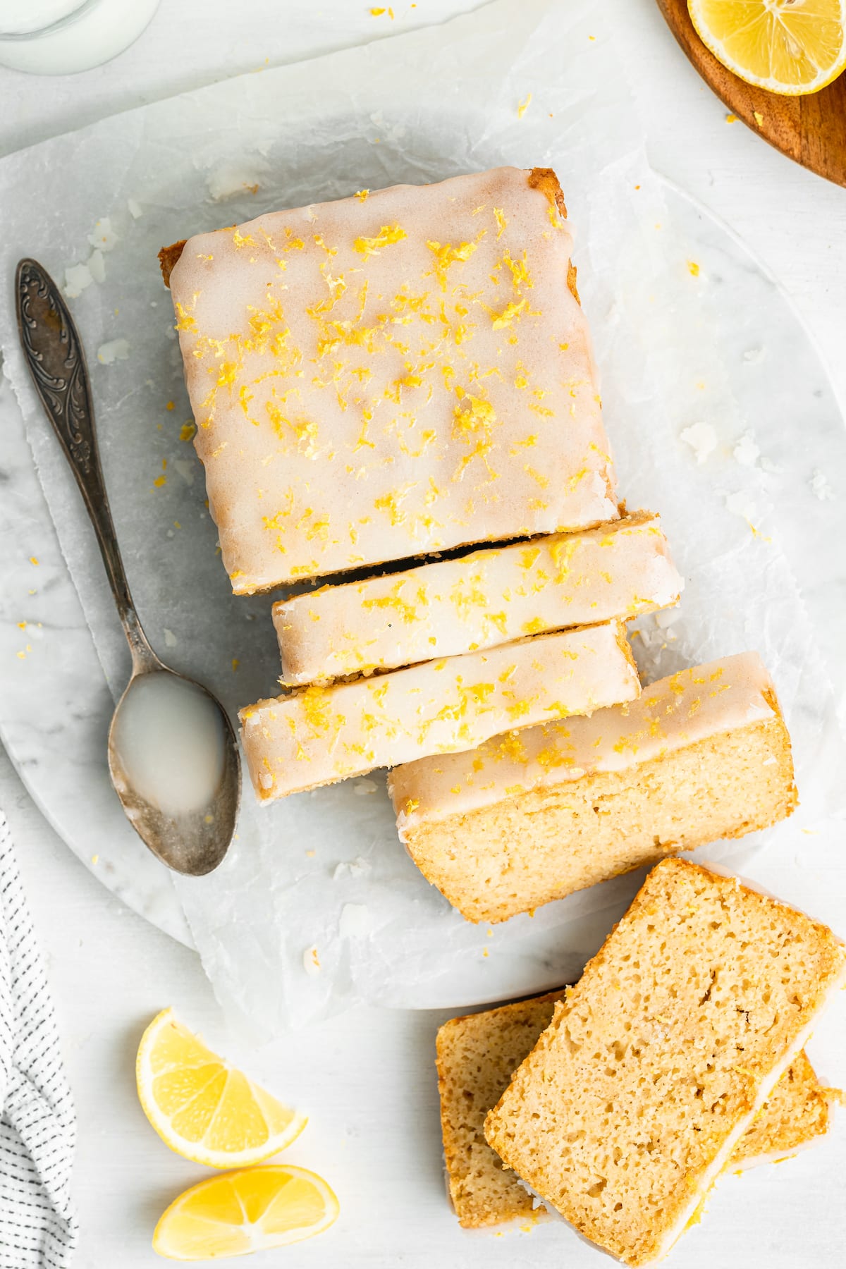 An overhead image of a lemon loaf cut into 5 slices. The lemon loaf is topped with a lemon glaze and lemon zest.