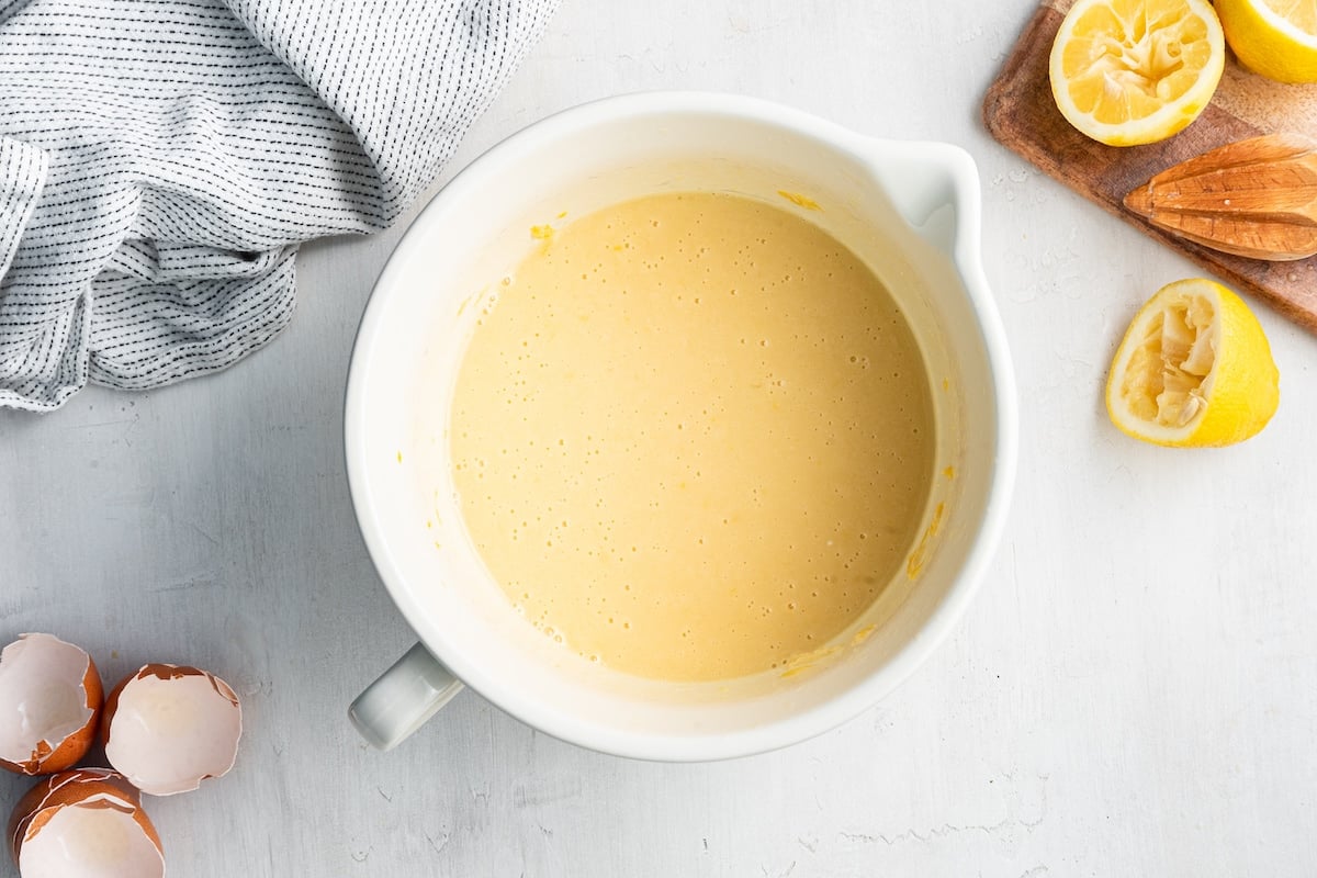 The wet ingredients for a lemon loaf combined in a white mixing bowl.