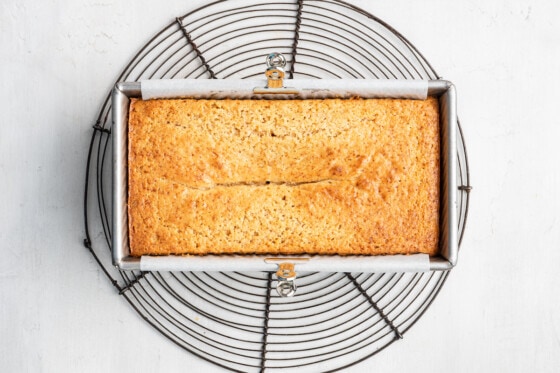 A fully baked lemon loaf that's lined with parchment paper cooling in a loaf pan.