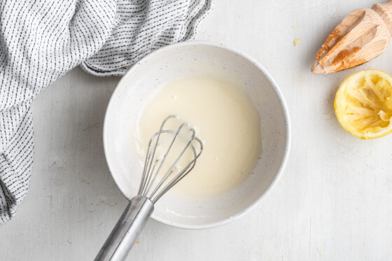 The ingredients for the lemon glaze combined in a small bowl with a whisk.