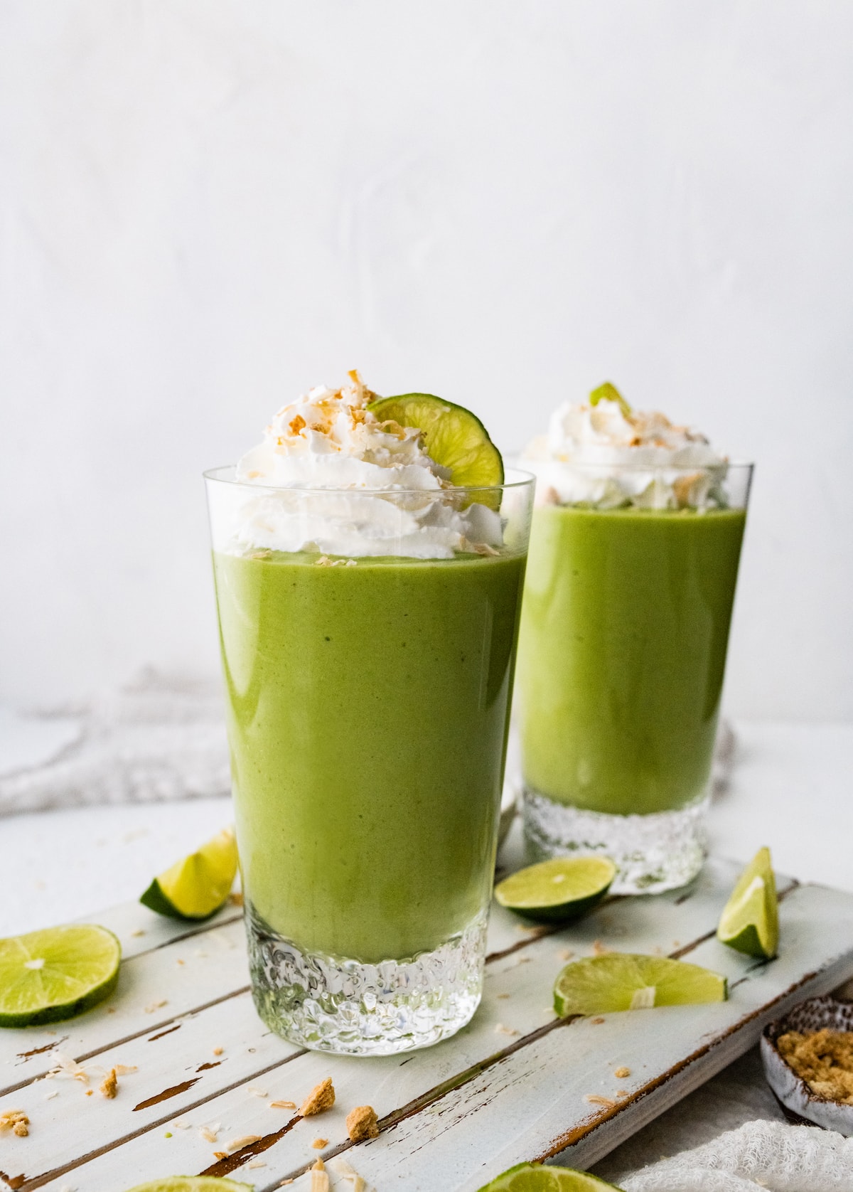 Two key lime pie smoothies topped with whipped cream and toasted coconut.
