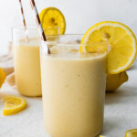 Two lemon smoothies with straws and fresh lemon slices.