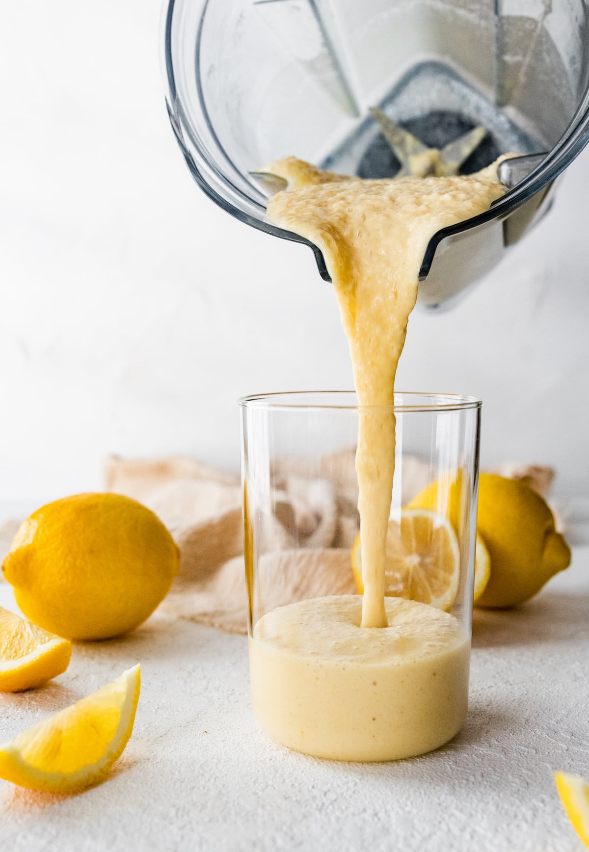 A lemon smoothie being poured into a glass.