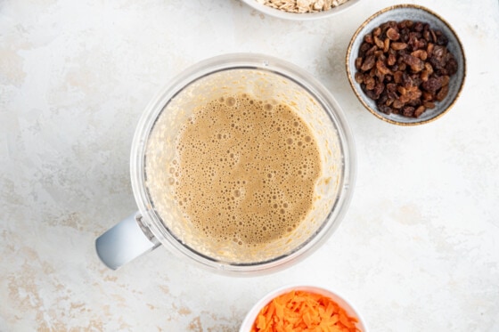 Ingredients for an oatmeal carrot cake blended together in the bowl of a blender.