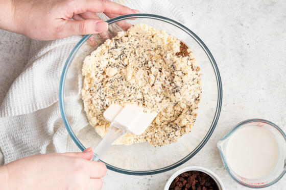 Woman's hands stirring dry ingredients for oatmeal raisin protein bars.