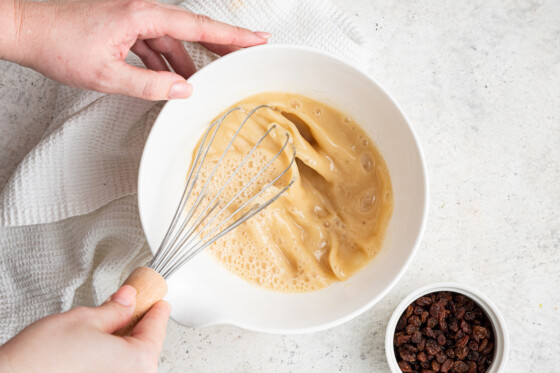 Woman's hands whisking wet ingredients for oatmeal raisin protein bars.