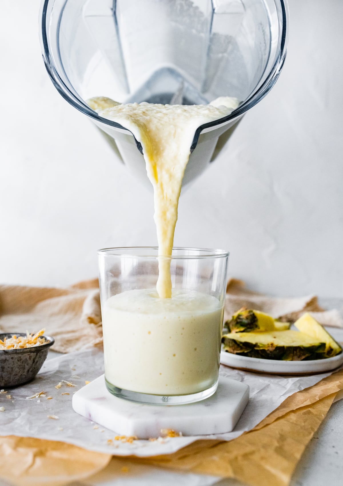 Pineapple smoothie being poured into a glass.