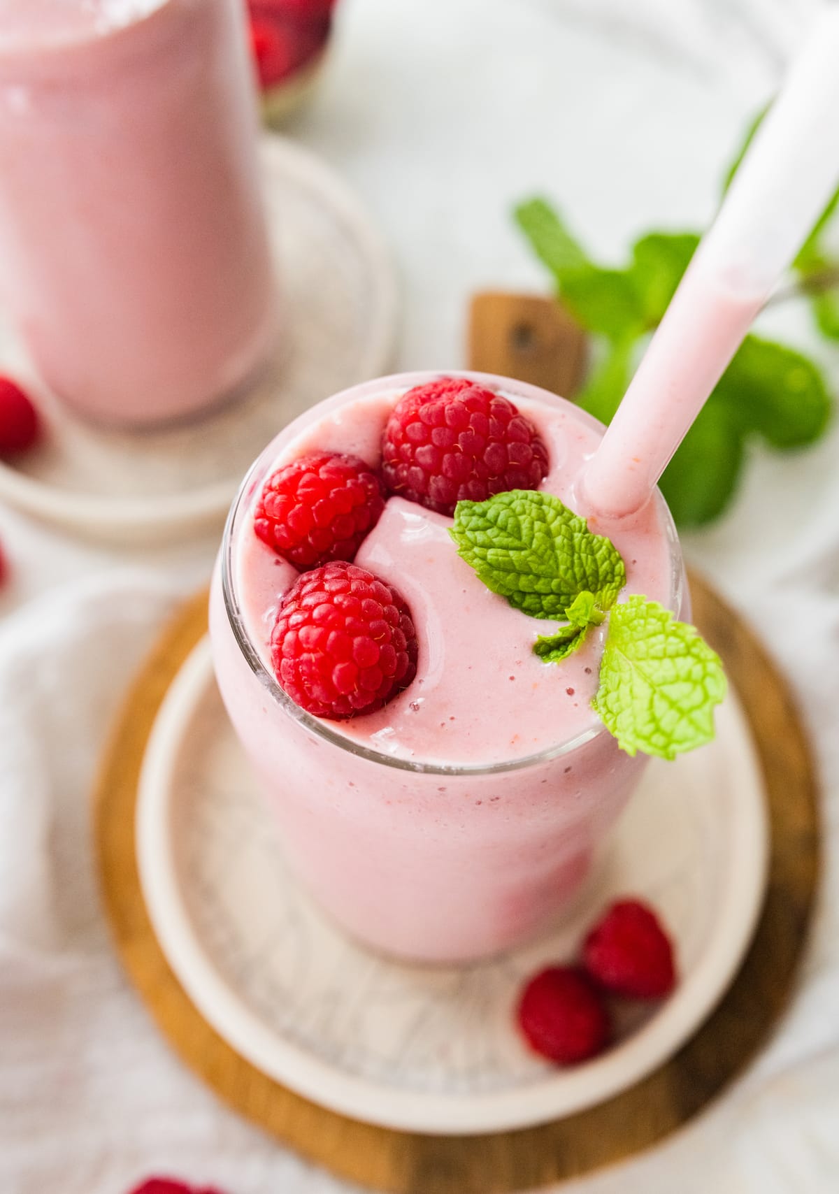 Overhead image of raspberry smoothie with straw and topped with fresh raspberries and mint.