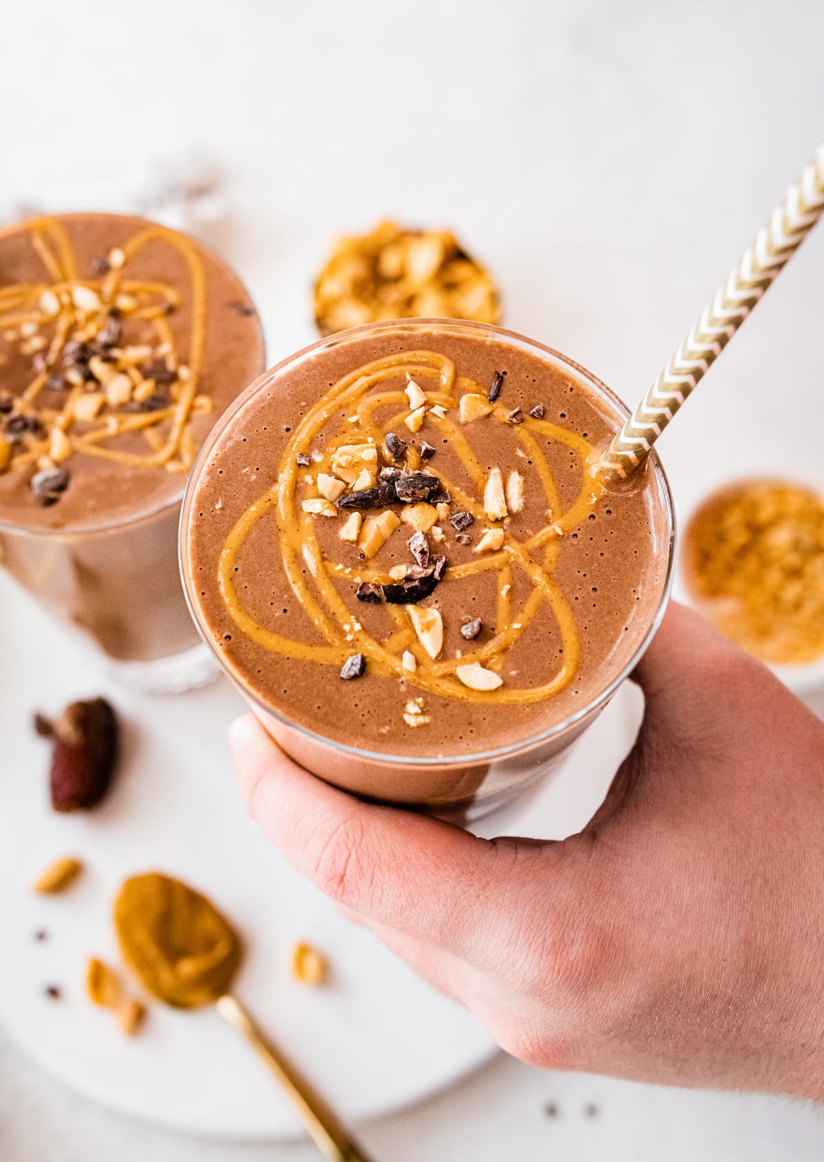 Woman's hand holding snickers protein smoothie with straw.