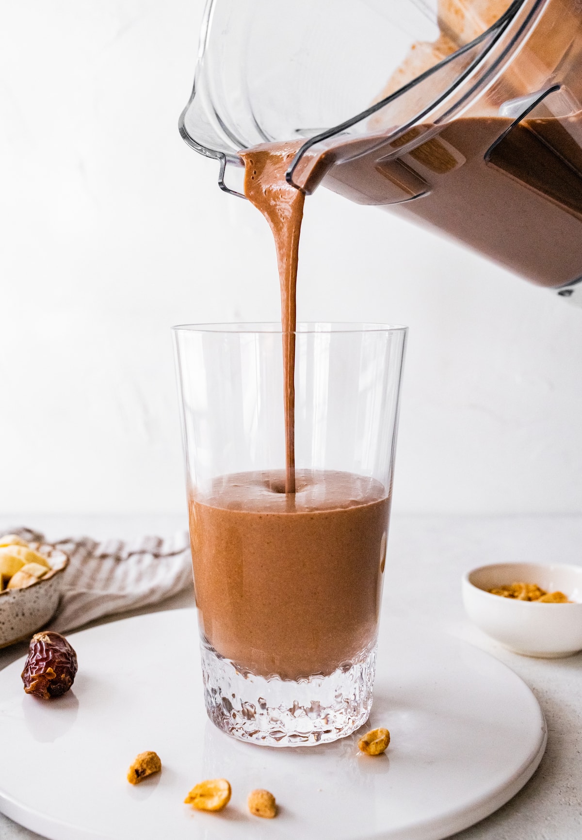 Snickers protein smoothie being poured into glass.