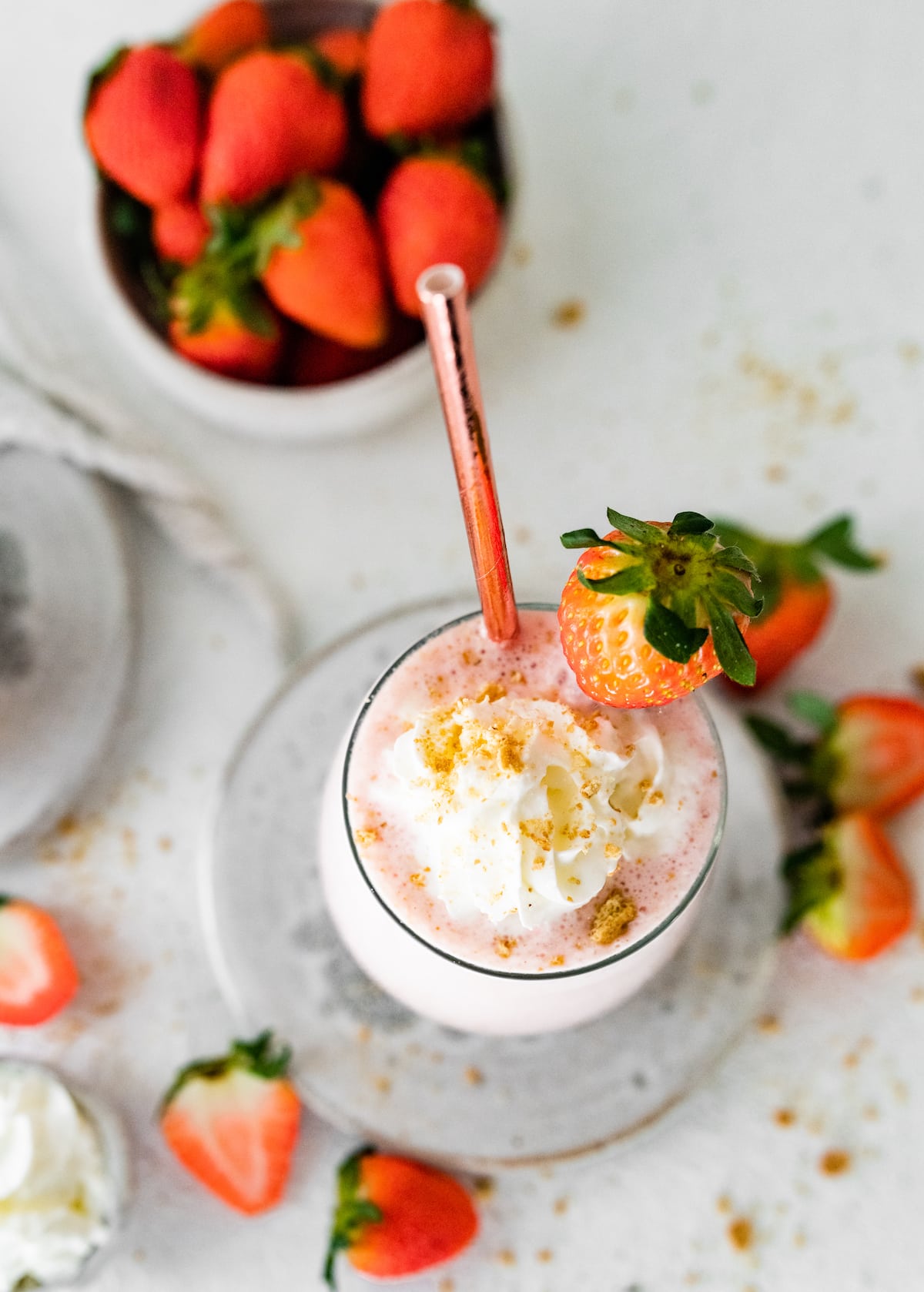 Overhead view of a strawberry cheesecake smoothie topped with graham crackers and whipped cream.